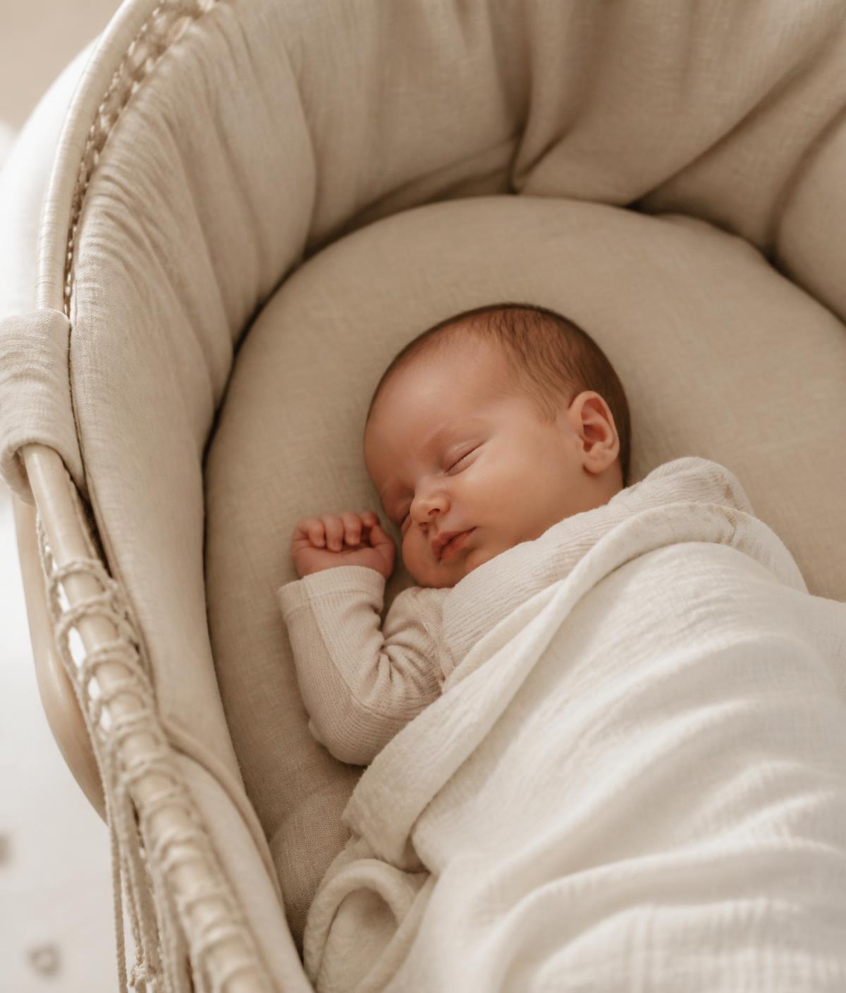 A newborn sleeping peacefully in a soft linen bassinet